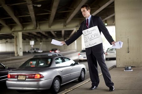 Recent La Salle graduate hands resumes out to passing cars during rush hour in Philadelphia